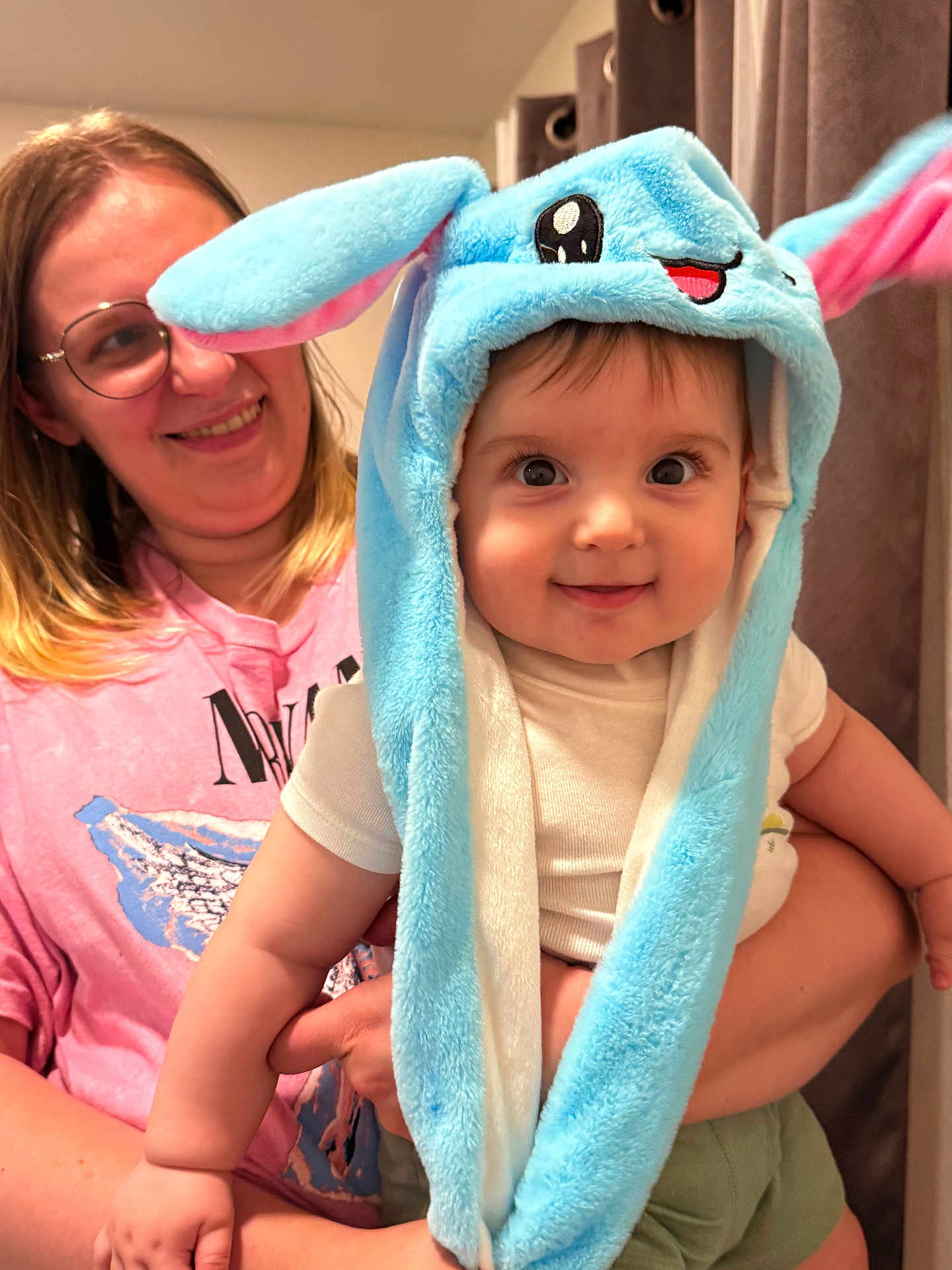 Zakhar is registered to the contest to win money with this photo: baby, child, woman, smile, hat, blue_hat, plush_hat, indoor, person, holding, cute, happy, face, clothing, glasses, pink_shirt, short_sleeve, portrait, expression, joy