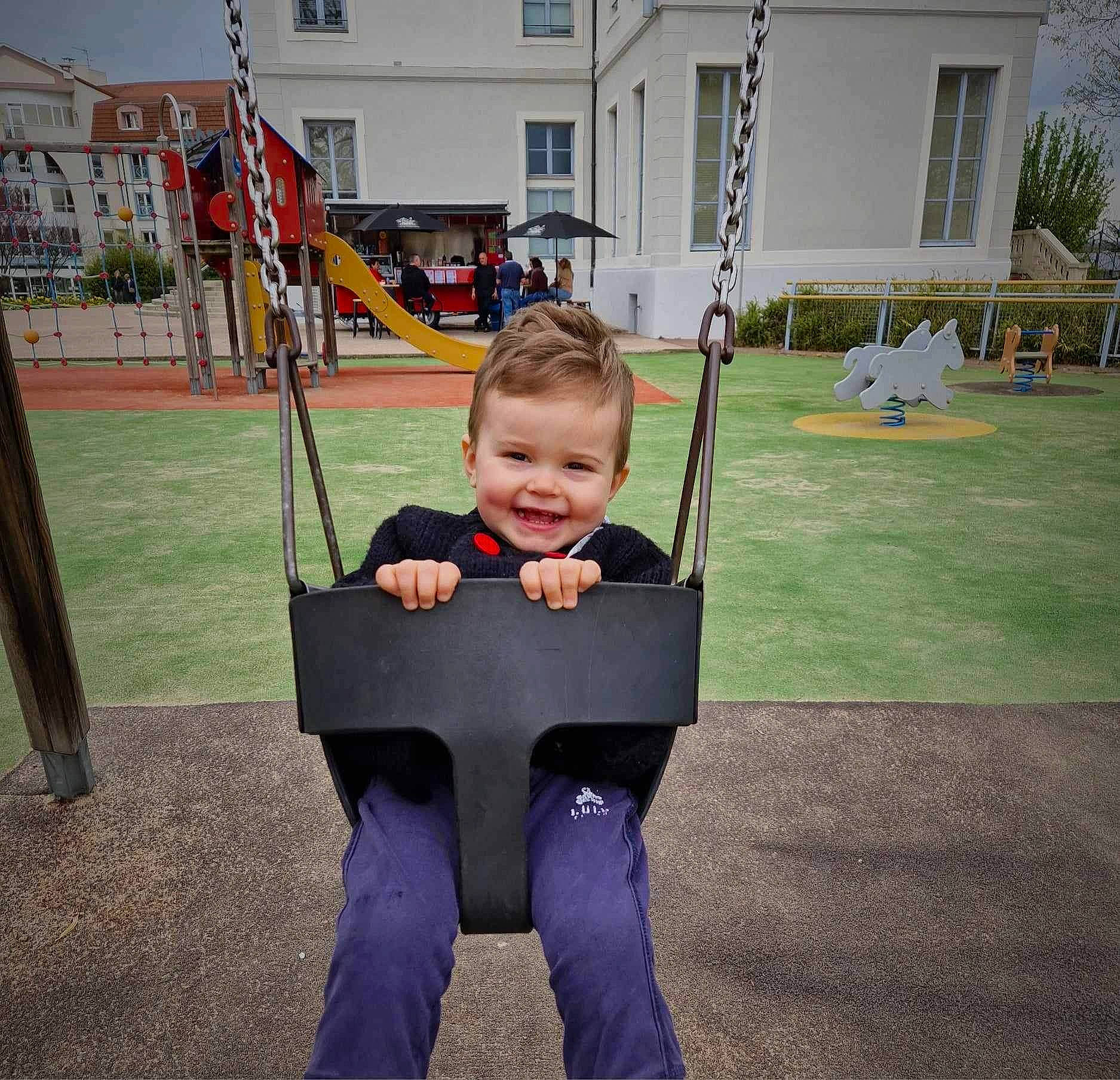 Djulyan a rejoint le concours — aidez-le/la à gagner de superbes lots ! baby, baby_toddler_clothing, building, city, fun, grass, happy, joy, leisure, outdoor_play_equipment, person, plant, play, playground, recreation, sleeve, smile, swing, t_shirt, toddler