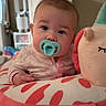 Wrenley joined the competition — help win amazing prizes! baby, pacifier, plush_toy, indoor, child, cute, face, portrait, soft_toy, infant, wearing_pajamas, looking_at_camera, colorful, cozy, furniture, television, modern_appliance, hand, sitting, expression