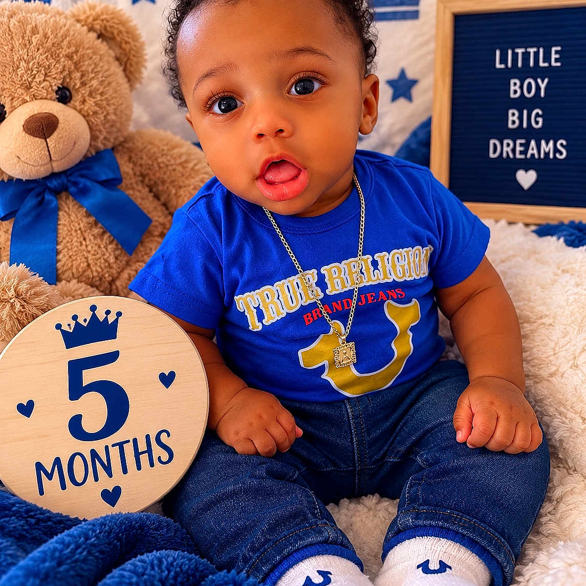 Amil joined the competition — help win amazing prizes! baby, infant, child, portrait, sitting, blue_outfit, curly_hair, smiling, wide_eyes, teddy_bear, stuffed_animal, blanket, nursery, milestone, five_months, wooden_sign, stars, crown, necklace, indoor