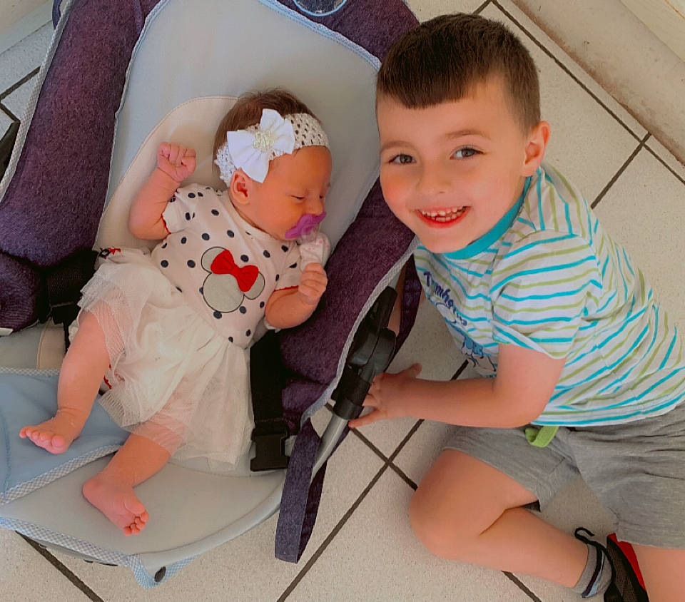 Maheddine participe au concours pour gagner de l'argent avec cette photo : baby, baby_toddler_clothing, chair, comfort, facial_expression, fun, human_body, joint, joy, knee, lap, leg, person, product, shorts, skin, smile, sneakers, sock, t_shirt