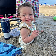 Wrenley joined the competition — help win amazing prizes! toddler, child, beach, sand, smile, curly_hair, bow, towel, sunny, outdoor, summer, vacation, happy, play, clothing, blue_sky, beach_umbrella, water_bottle, footwear, polka_dot_bag