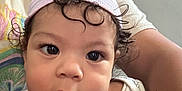 Azariah is registered to the contest to win money with this photo: baby, child, person, face, hat, curl, blanket, smile, adult, curly_hair, closeup, indoor, tshirt, holding, expression, cute, infant, portrait, skin, young