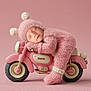 Zoey is registered to the contest to win money with this photo: newborn, baby, sleeping, pink, knitted_outfit, motorcycle, toy, cute, cozy, pom_poms, soft_background, portrait, child, infant, resting, studio, adorable, warm, tiny, peaceful