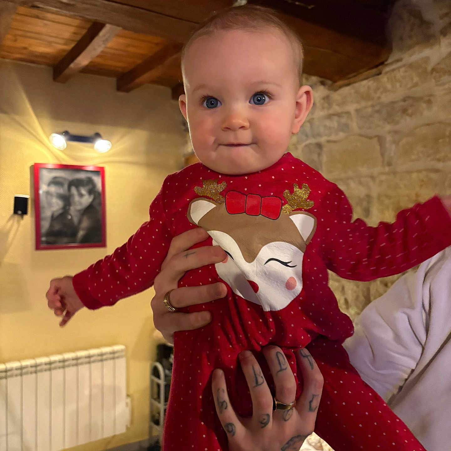 Siobane participe au concours pour gagner de l'argent avec cette photo : baby, child, cute, floor_tiles, holding, home_interior, indoor, lighting, person, portrait, radiator, red_clothing, reindeer_design, ring, shoes, smiling, stone_wall, tattooed_hands, watch, wooden_beams