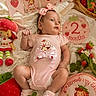 baby, basket, blanket, celebration, child, cute, decorations, face, flowers, headband, infant, lying_down, milestone_sign, onesie, pink_clothing, plush_toy, portrait, socks, soft_toys, strawberry