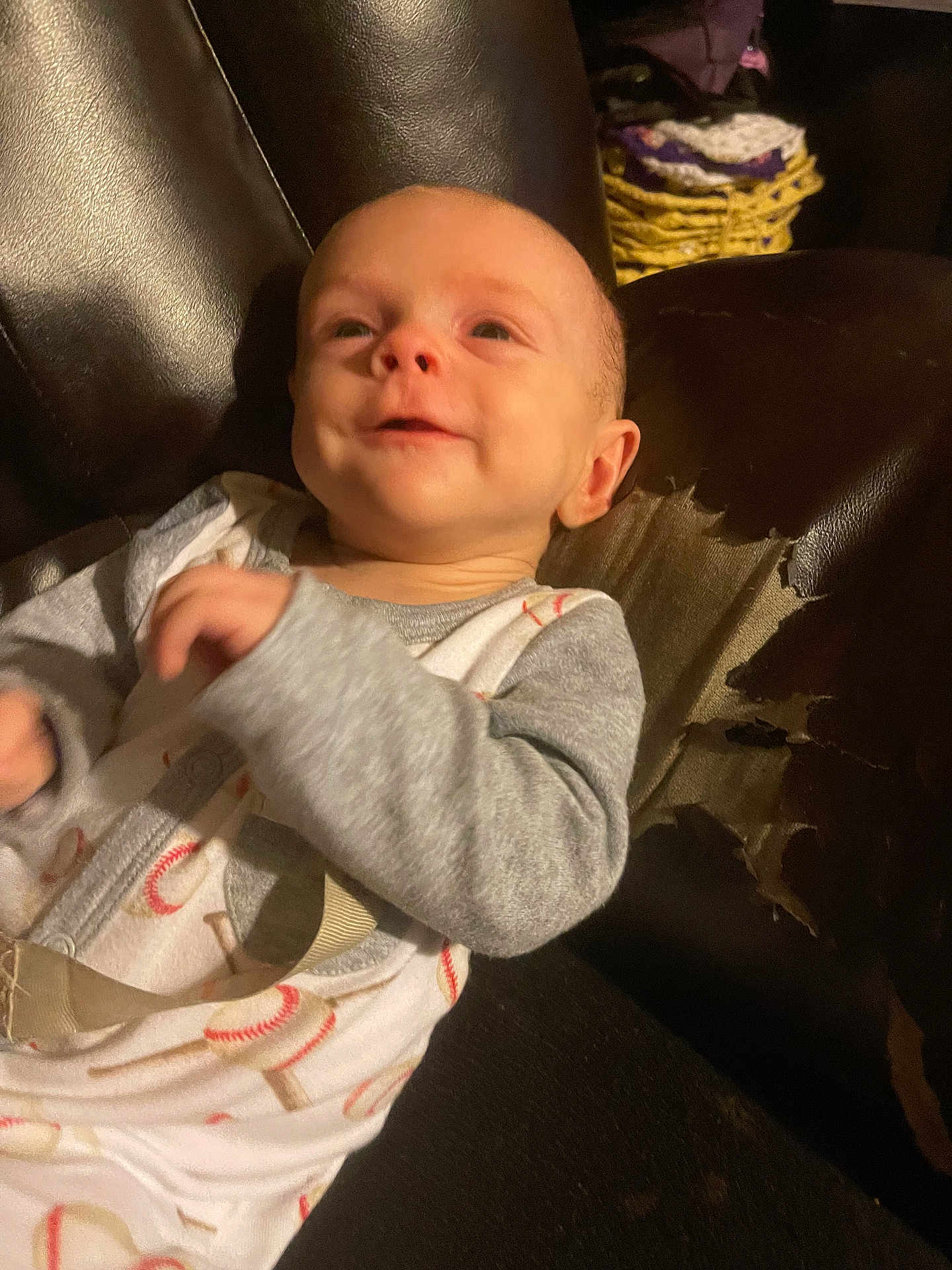Sawyer is registered to the contest to win money with this photo: baby, child, smile, pajamas, baseball_print, face, leather_chair, worn_out, indoor, cozy, person, infant, cute, happy, sitting, clothing, background, fabric, seat, relax