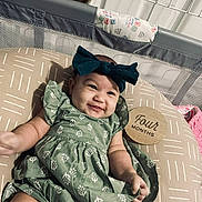 Hadley joined the competition — help win amazing prizes! baby, infant, smile, green_dress, headband, bow, cushion, wooden_sign, four_months, playpen, baby_accessories, patterned_fabric, lying_down, happy, child, indoors, milestone, cute, person, portrait