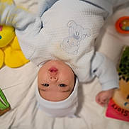 Bella Mia is registered to the contest to win money with this photo: baby, infant, onesie, hat, blanket, toy, soft_toy, teddy_bear, lying_down, cute, child, indoor, bed, colorful, pout, face, person, clothing, comfort, playtime