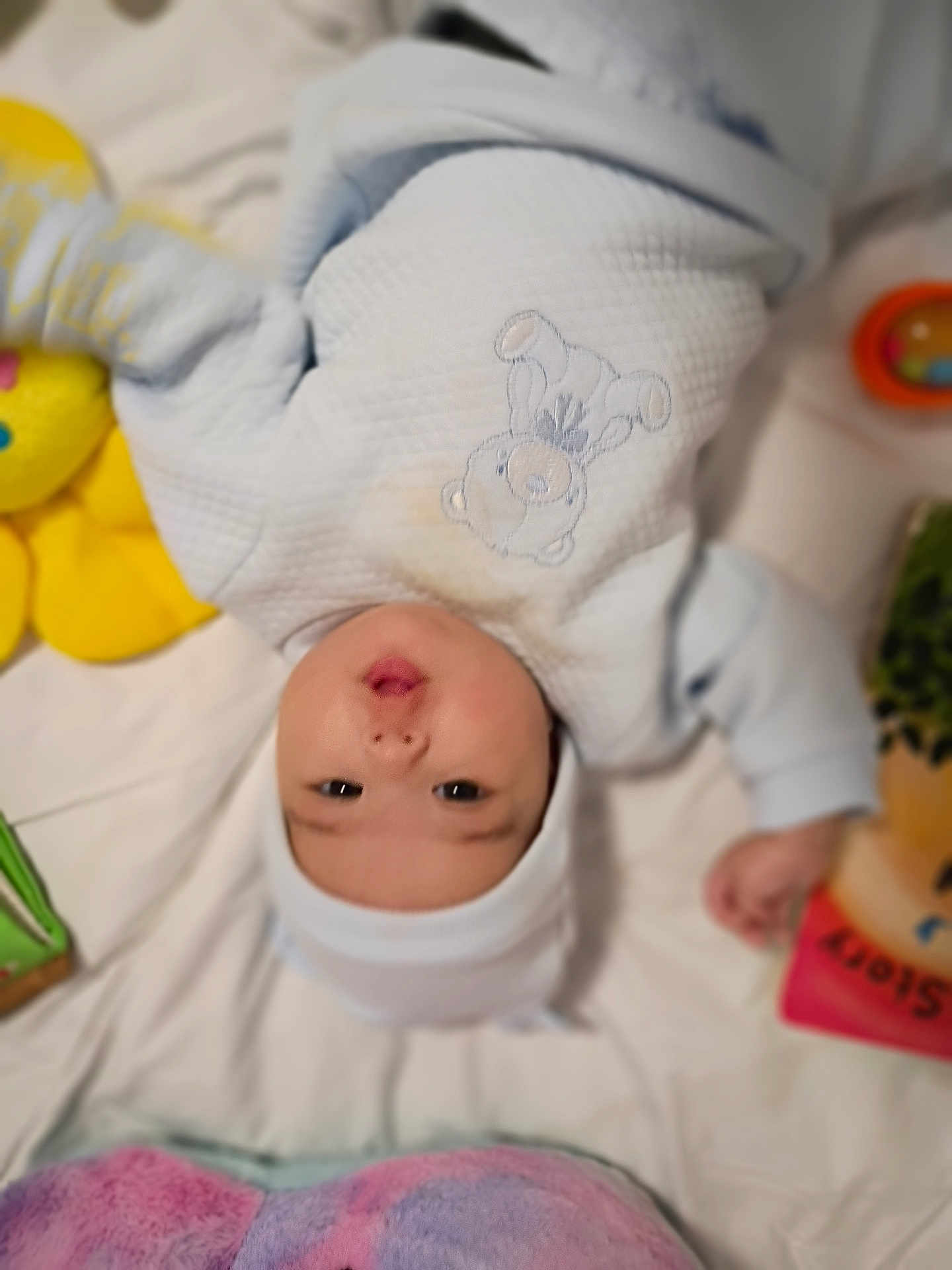 Bella Mia is registered to the contest to win money with this photo: baby, infant, onesie, hat, blanket, toy, soft_toy, teddy_bear, lying_down, cute, child, indoor, bed, colorful, pout, face, person, clothing, comfort, playtime