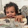 Zavain is registered to the contest to win money with this photo: toddler, child, baby, curly_hair, smiling, face, portrait, indoors, playpen, highchair, padded_rail, animal_pattern, elephant, giraffe, crocodile, door, furniture, hands, happy, photography