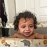 Zavain is registered to the contest to win money with this photo: baby, child, infant, curly_hair, smiling, face, portrait, indoor, play_mat, safari_theme, elephant, giraffe, crocodile, animal_pattern, nursery, home, seated, looking_at_camera, happy, photography