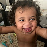 Zavain is registered to the contest to win money with this photo: baby, child, infant, smiling, laughing, curly_hair, portrait, face, eyes, teeth, indoor, nursery, diaper, toy, crib, changing_table, blanket, furniture, happy, close_up