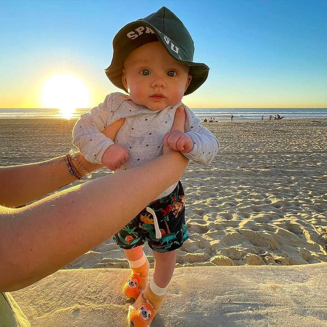 Madden joined the competition — help win amazing prizes! arm, azure, beach, body_of_water, cap, cool, finger, gesture, hand, happy, hat, headgear, headwear, light, people_in_nature, people_on_beach, person, sky, sleeve, sunlight