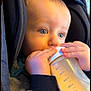 baby, bottle, milk, hands, face, blue_eyes, clothing, car_seat, child, infant, feeding, closeup, cute, expression, skin, fingers, sitting, warm, indoors, portrait