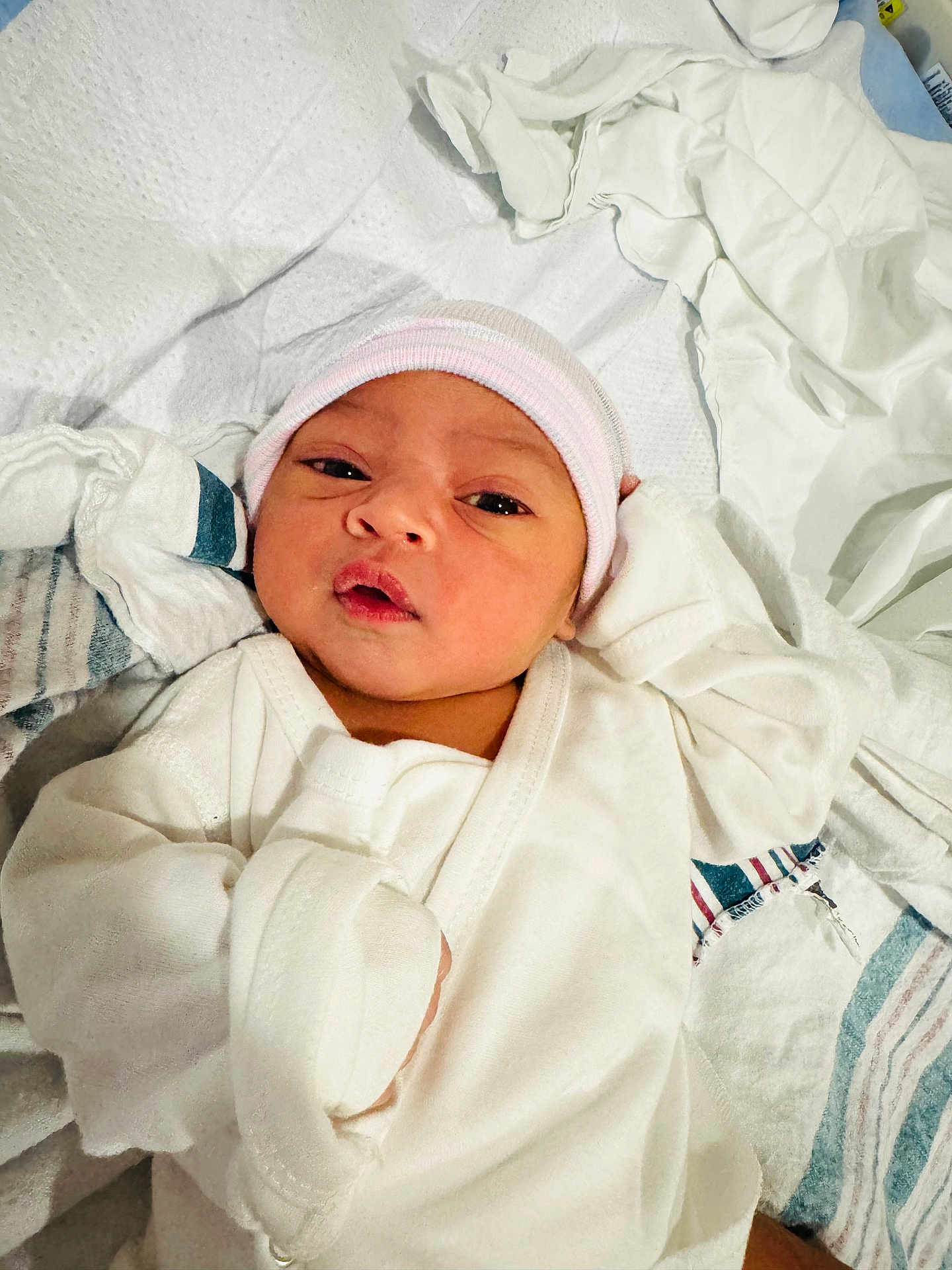 Amirah is registered to the contest to win money with this photo: newborn, baby, infant, clothing, hat, bed, blanket, towel, white, soft, cute, face, portrait, lying_down, indoors, closeup, person, sleepwear, wrapped, resting