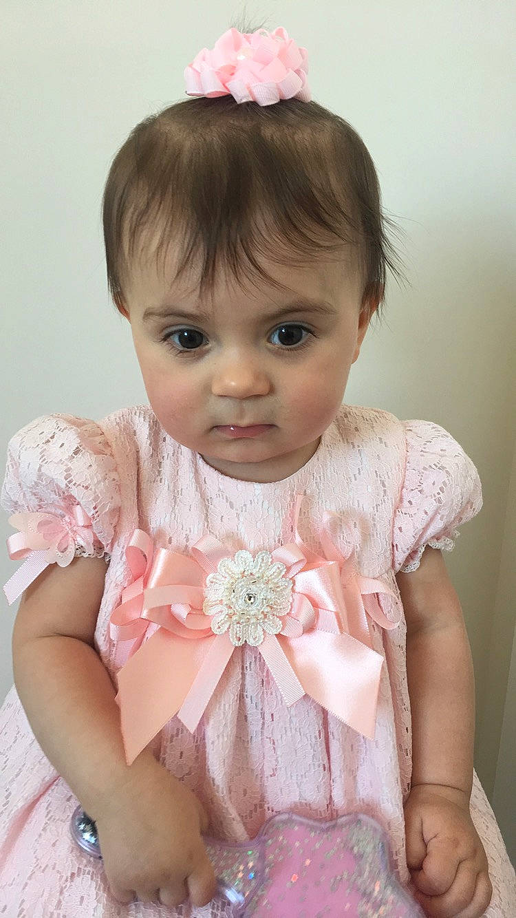 Effie is registered to the contest to win money with this photo: baby, baby_toddler_clothing, brown_hair, cheek, child, child_model, dress, fashion_accessory, hair, hair_accessory, hairstyle, peach, person, pink, skin, smile, textile, toddler