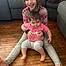 Shaddai is registered to the contest to win money with this photo: child, baby, smiling, sitting, floor, wooden_floor, living_room, couch, blanket, sweater, pink_shirt, happy, person, indoors, family, feet, hair, holding, playful, casual_clothing