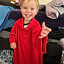toddler, child, smiling, red_shirt, oversized_clothing, indoor, bedroom, carpet, blanket, cat_picture, furniture, happy, person, portrait, reaching_out, casual, home, cute, young_child, playful