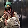 puppy, dog, person, selfie, mirror, elevator, phone, smartphone, popsocket, beanie, hat, sweater, knitwear, hand, holding, reflection, indoor, white_puppy, cute, portrait