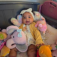 Iniah joined the competition — help win amazing prizes! baby, child, infant, smiling, sitting, portrait, headband, bow, onesie, clothing, stuffed_animal, plush_toy, elephant_toy, teddy_bear, winnie_the_pooh, crib, bedding, nursery, indoors, colorful