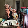 Iniah is registered to the contest to win money with this photo: child, toddler, baby, parent, family, mirror_selfie, bathroom, sink, soap_dispenser, shower_cap, pajamas, smiling, portrait, indoors, home, open_door, gift_boxes, countertop, reflection, smartphone