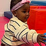 toddler, child, indoor, playroom, headband, striped_sweater, curious, toy, colorful, red_basket, pink_mat, blue_toy, smiling, caucasian_skin, short_hair, seated, happy, exploring, clothing, playtime