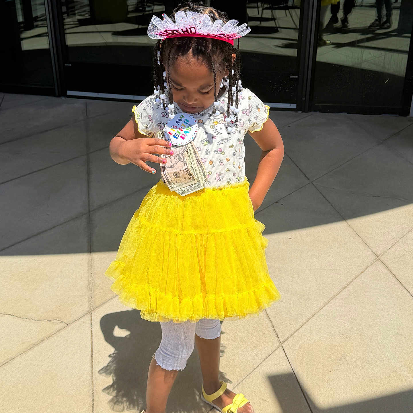 Kaidence Amarri is registered to the contest to win money with this photo: child, girl, birthday, yellow_skirt, sandals, sunlight, shadow, tiara, braids, outdoor, concrete, celebration, dress, white_tights, person, happy, beads, headwear, fashion, casual