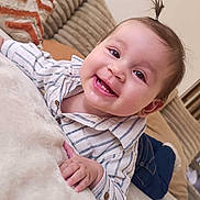 Aya a rejoint le concours — aidez-le/la à gagner de superbes lots ! baby, child, infant, smiling, tooth, top_knot, striped_shirt, button_down, couch, pillow, blanket, hand, drool, happy, portrait, close_up, jeans, home_interior, cute, toddler
