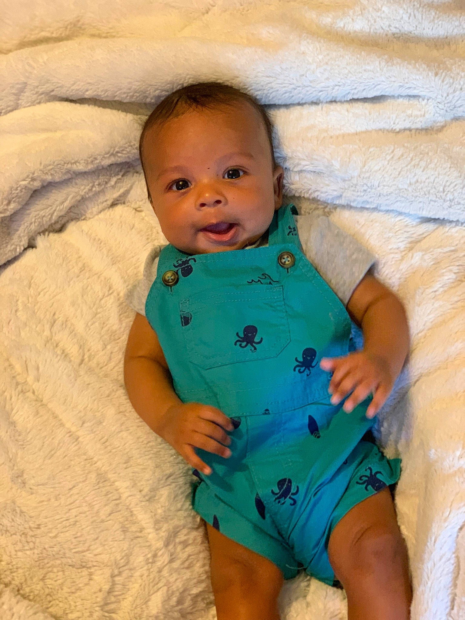 Zakai is registered to the contest to win money with this photo: baby, baby_toddler_clothing, cheek, child, comfort, eye, finger, happy, head, human_body, linens, mouth, nail, neck, nose, pattern, person, skin, sleeve, textile
