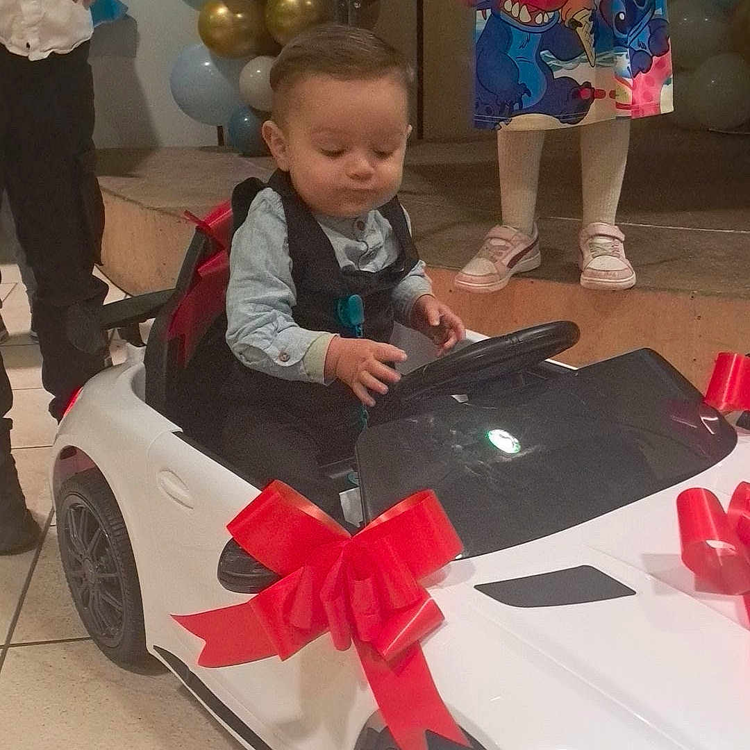 Djuan participe au concours pour gagner de l'argent avec cette photo : balloons, cartoon_print, celebration, child, decorations, dress, event, floor_tile, formal_clothing, girl, indoor, man, party, people, red_bow, shoes, stage, steering_wheel, toddler, toy_car