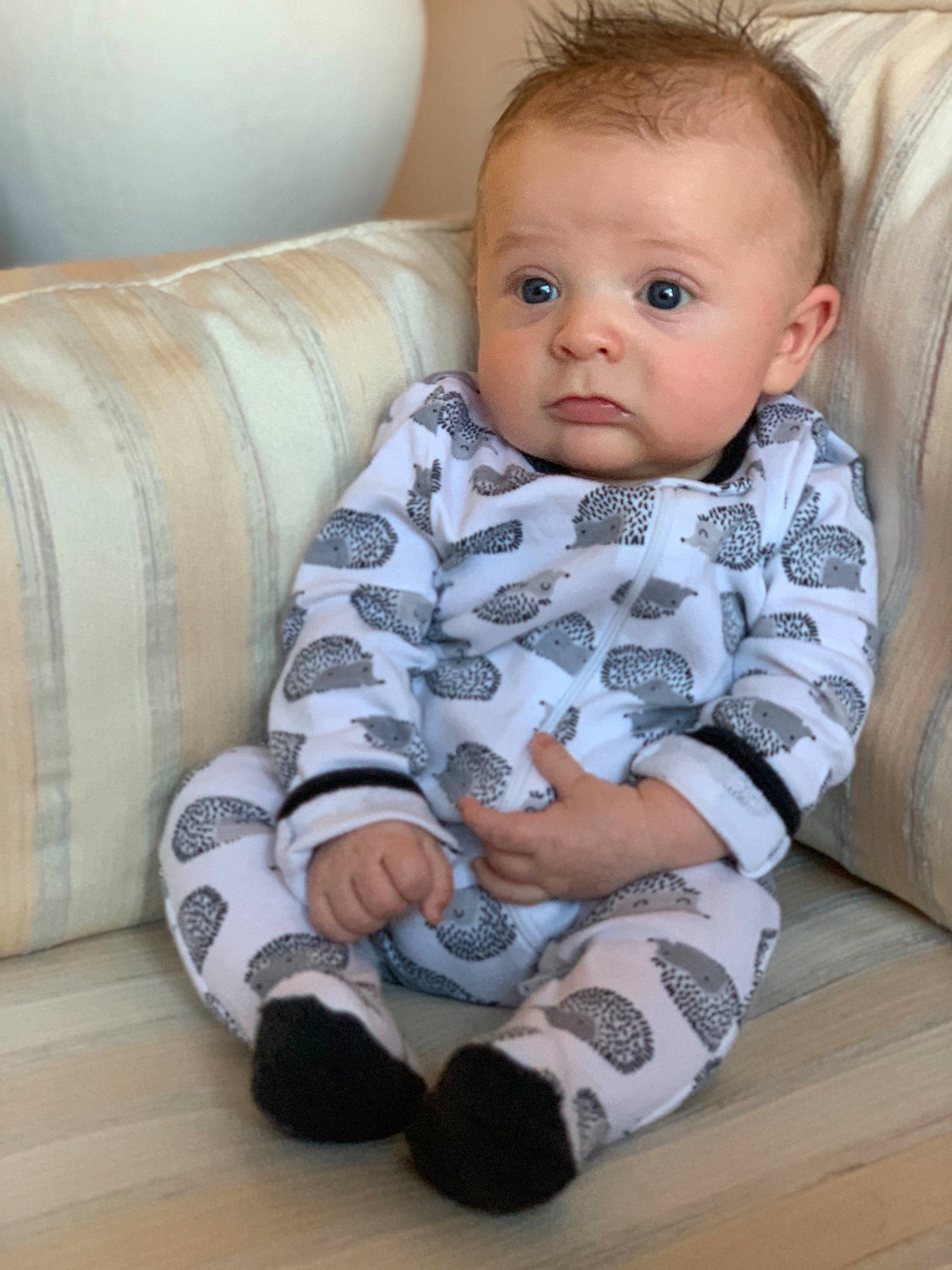 Baker is registered to the contest to win money with this photo: ankle, baby, baby_toddler_clothing, cheek, child, comfort, couch, ear, eyelash, flooring, foot, human, lap, living_room, mammal, mouth, person, sitting, sock, toddler