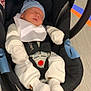 newborn, baby, infant, car_seat, sleeping, blue_hat, white_clothing, mittens, socks, floor, stripes, baby_buckle, infant_seat, indoor, child, person, resting, secure, cozy, transportation