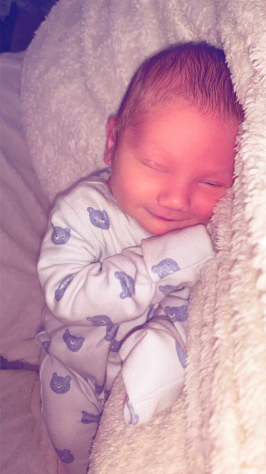 Malachi is registered to the contest to win money with this photo: baby, newborn, sleeping, blanket, onesie, bear_pattern, cozy, cute, infant, soft_texture, smile, child, resting, warm, cute_outfit, peaceful, comfort, indoors, portrait, sleep