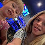 child, young_woman, selfie, smile, tongue_out, indoor, restaurant, bar, television, bottles, chair, table, blonde_hair, casual_clothing, person, face, happy, fun, friends, people