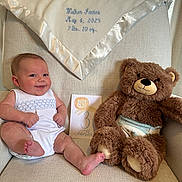Walker is registered to the contest to win money with this photo: baby, teddy_bear, armchair, blanket, diaper, card, window, curtain, smile, infant, child, stuffed_animal, cloth, fabric, indoor, portrait, cute, sitting, light, happy