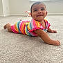 baby, infant, child, smiling, rainbow_striped_clothing, carpet, indoor, crawling, cute, happy, person, toddler, bright_colors, playful, room, window, natural_light, skin, face, eyes