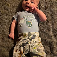 Bobby joined the competition — help win amazing prizes! baby, infant, towel, clothing, dinosaur, pattern, cute, lying_down, person, child, apparel, fabric, hand, face, expression, indoor, text, sleepwear, soft_texture, union_jack