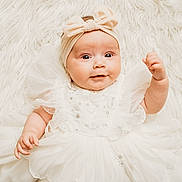 Liliana is registered to the contest to win money with this photo: baby, infant, child, white_dress, headband, bow, fluffy_background, cute, portrait, smiling, lying_down, soft_texture, adorable, closeup, baby_fashion, innocent, happy, person, toddler, charming