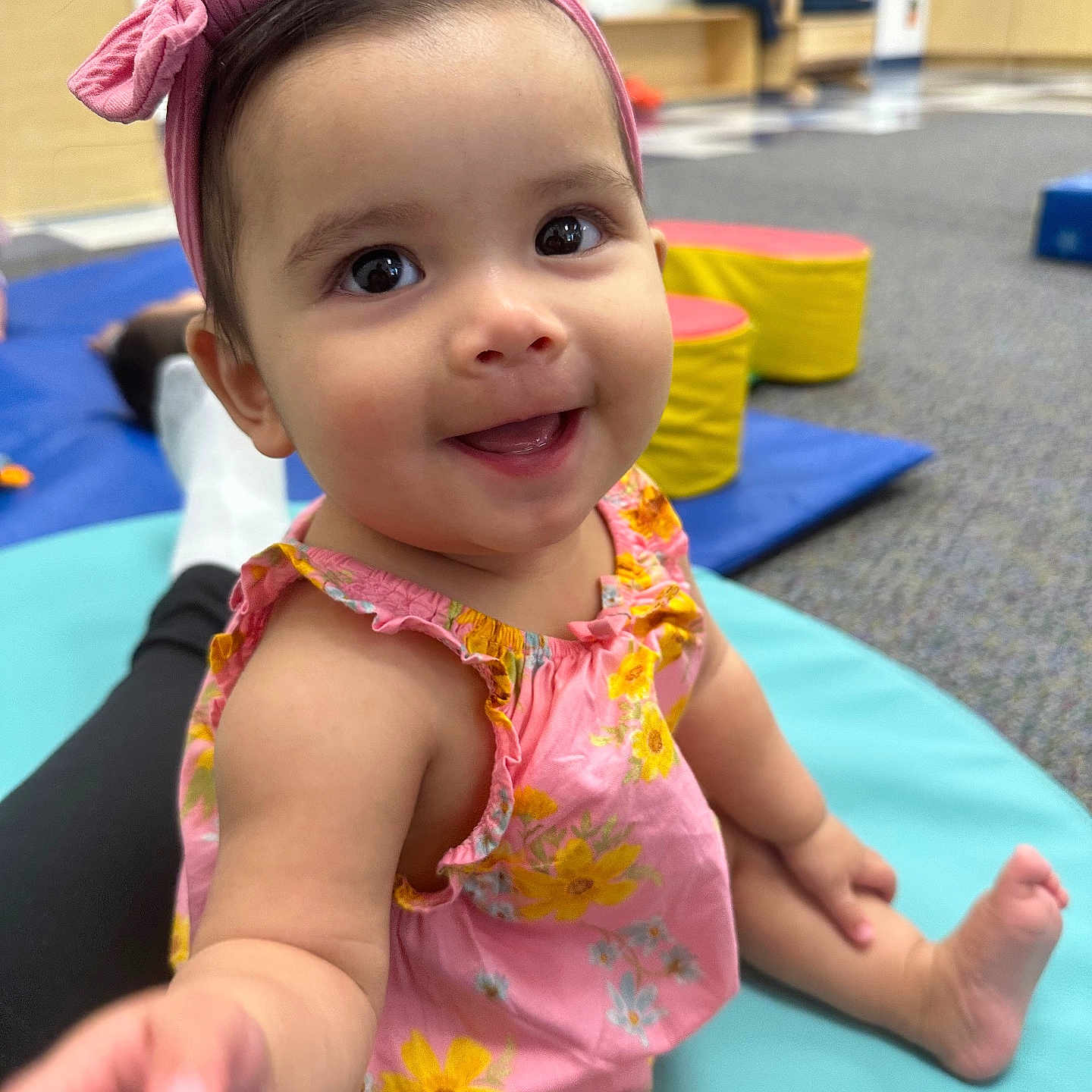 Kailee is registered to the contest to win money with this photo: baby_clothes, carpet, child, colorful, cute, expression, furniture, happy, headband, indoor, mat, person, pink_bow, play_area, playful, sitting, skin, smiling, toddler, toy