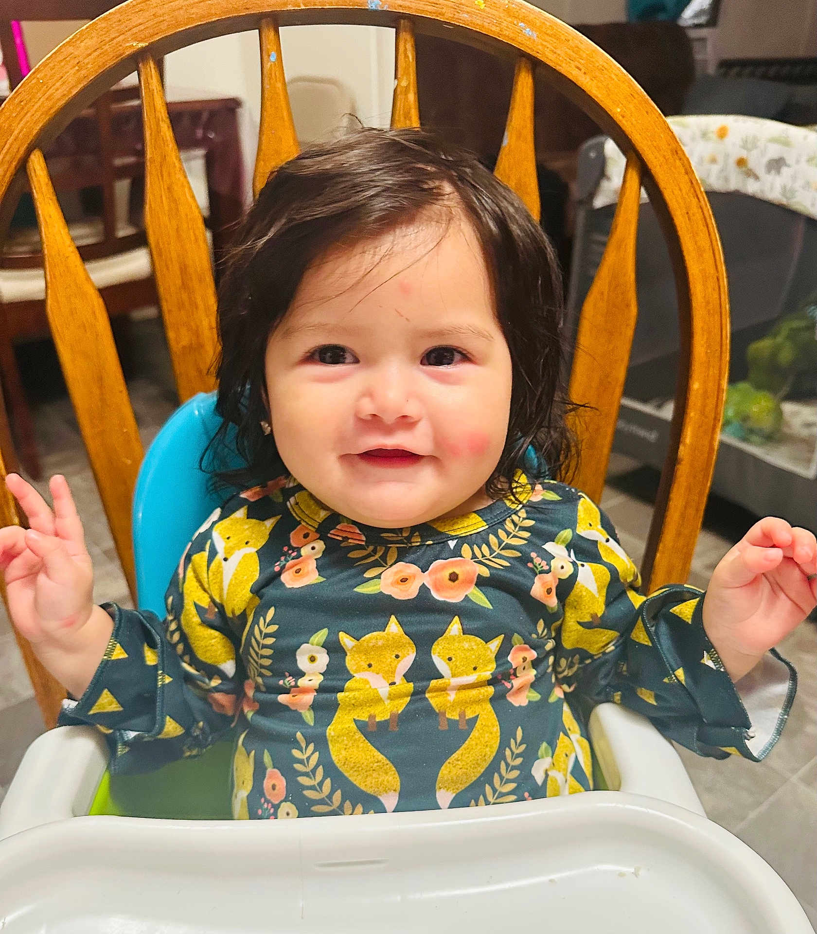 Nahomy joined the competition — help win amazing prizes! baby, child, high_chair, smiling, indoor, wooden_chair, face, cute, clothing, patterned_shirt, fox_print, happy, person, small_hands, dining_room, furniture, table, hair, rosy_cheeks, infant