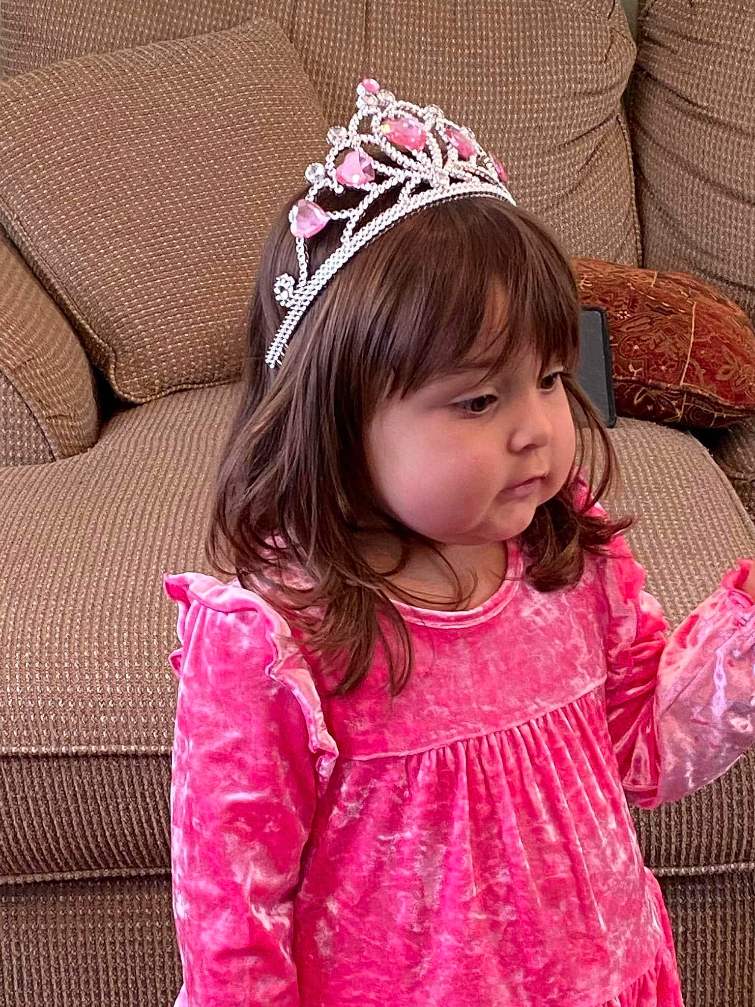 Lilianna is registered to the contest to win money with this photo: baby_toddler_clothing, black_hair, cap, child, cool, couch, dress, face, happy, head, magenta, neck, outerwear, person, pink, purple, skin, sleeve, textile, tiara