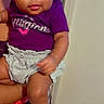 Kailani is registered to the contest to win money with this photo: baby, child, infant, person, face, purple_shirt, shorts, pink_bow, indoor, carpet, door, holding, cute, eyes, skin, arm, leg, foot, clothing, portrait