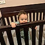 baby, infant, crib, wooden_crib, mattress, baby_pajamas, striped_onesie, hand, face, eyes, teething, chewing, gaze, standing, nursery, bedroom, cute, adorable, furniture, slats