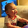 architecture, baby, babylaughing, building, clothing, couch, cushion, face, furniture, happy, head, homedecor, indoors, laughing, person, photography, portrait, sitting, smile, t_shirt