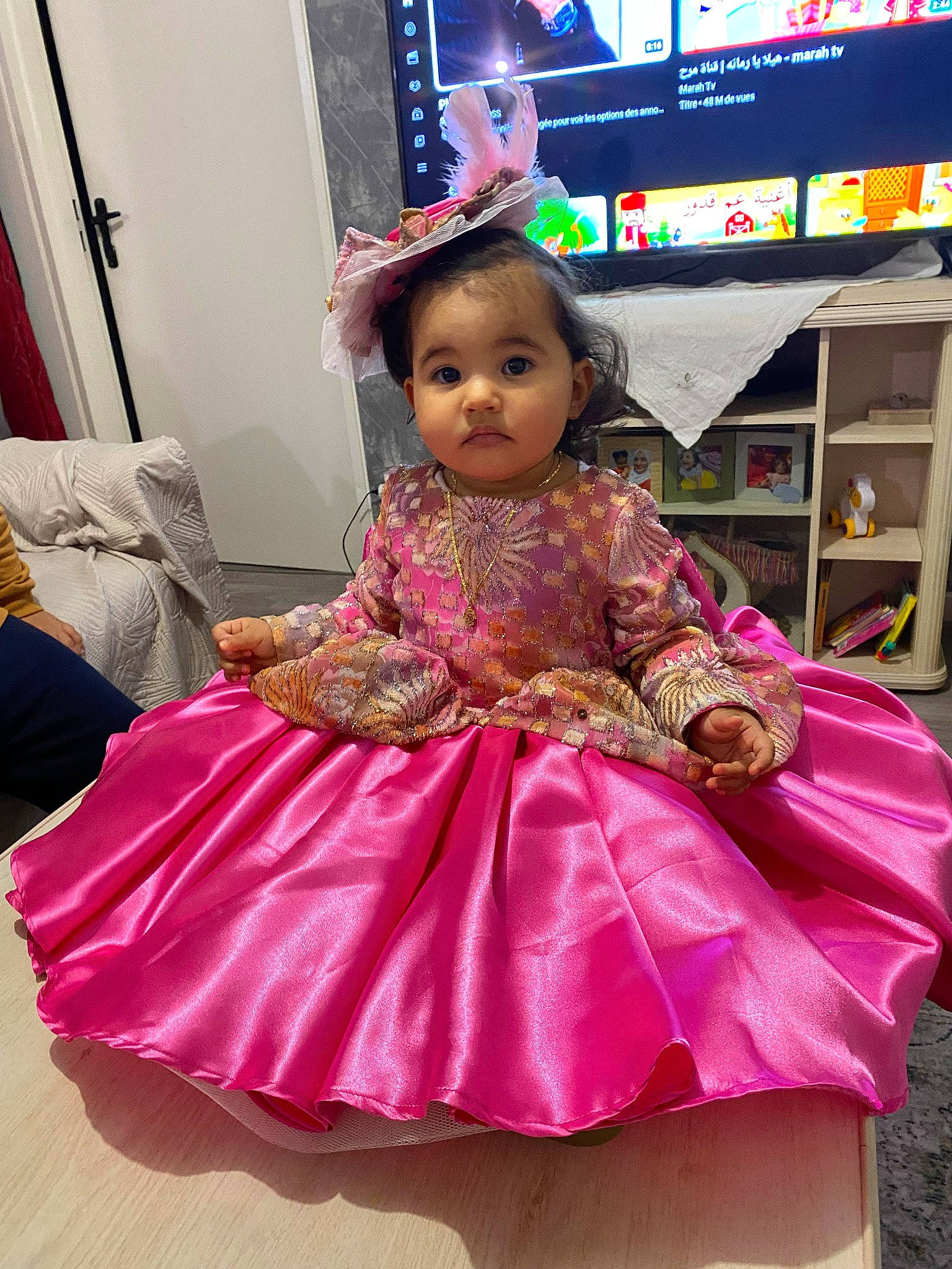 Lyn participe au concours pour gagner de l'argent avec cette photo : baby_toddler_clothing, child, costume, dress, embellishment, event, fashion_design, flooring, fun, happy, magenta, person, pink, purple, ruffle, sitting, skin, television, textile, toddler