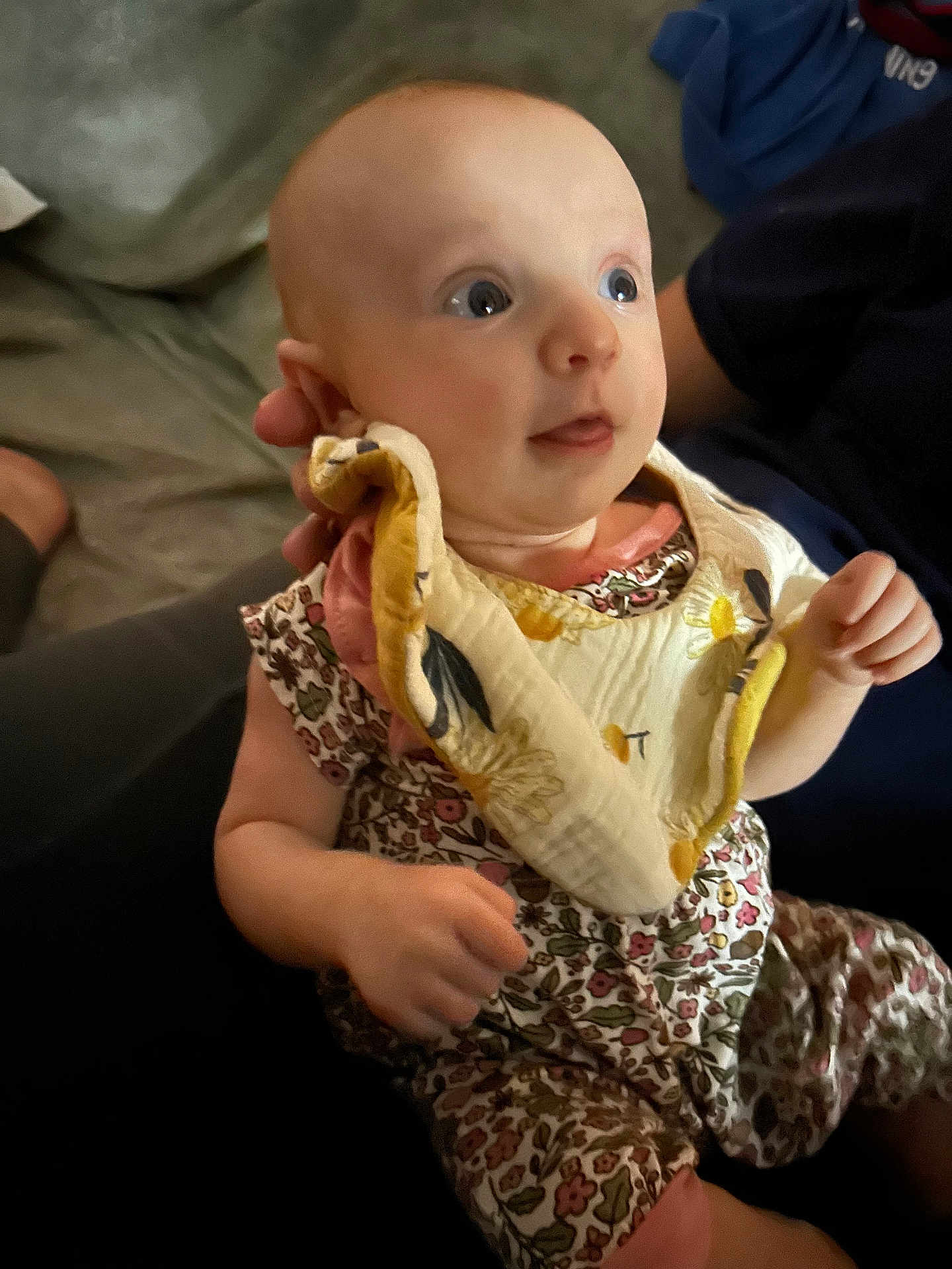 Marliese is registered to the contest to win money with this photo: baby, infant, child, person, floral_clothing, bib, curious_expression, indoor, seated, hand, face, head, skin, eyes, sleeveless, holding, fabric, candid, portrait, cute