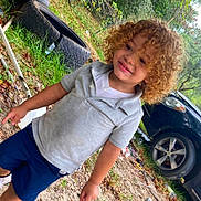 Adonis joined the competition — help win amazing prizes! car, casual_clothing, child, curly_hair, daylight, dirt, grass, grey_shirt, happy, leaves, nature, navy_shorts, outdoor, person, playful, smiling, tires, toddler, trees, young_child
