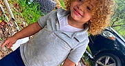 Adonis joined the competition — help win amazing prizes! car, casual_clothing, child, curly_hair, daylight, dirt, grass, grey_shirt, happy, leaves, nature, navy_shorts, outdoor, person, playful, smiling, tires, toddler, trees, young_child