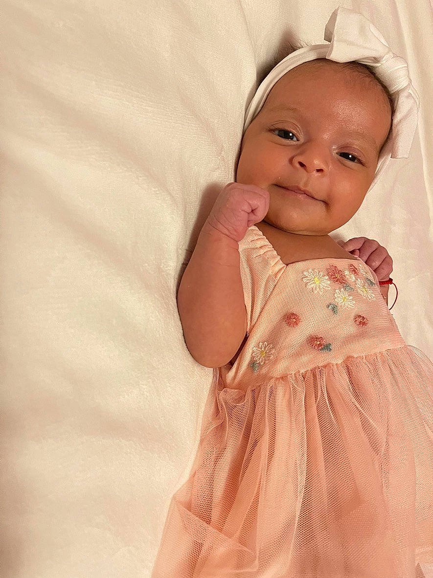 Sonia joined the competition — help win amazing prizes! arm, baby, baby_toddler_clothing, cheek, child, comfort, day_dress, dress, embellishment, gesture, hand, happy, linens, one_piece_garment, pattern, peach, person, ruffle, skin, sleeve